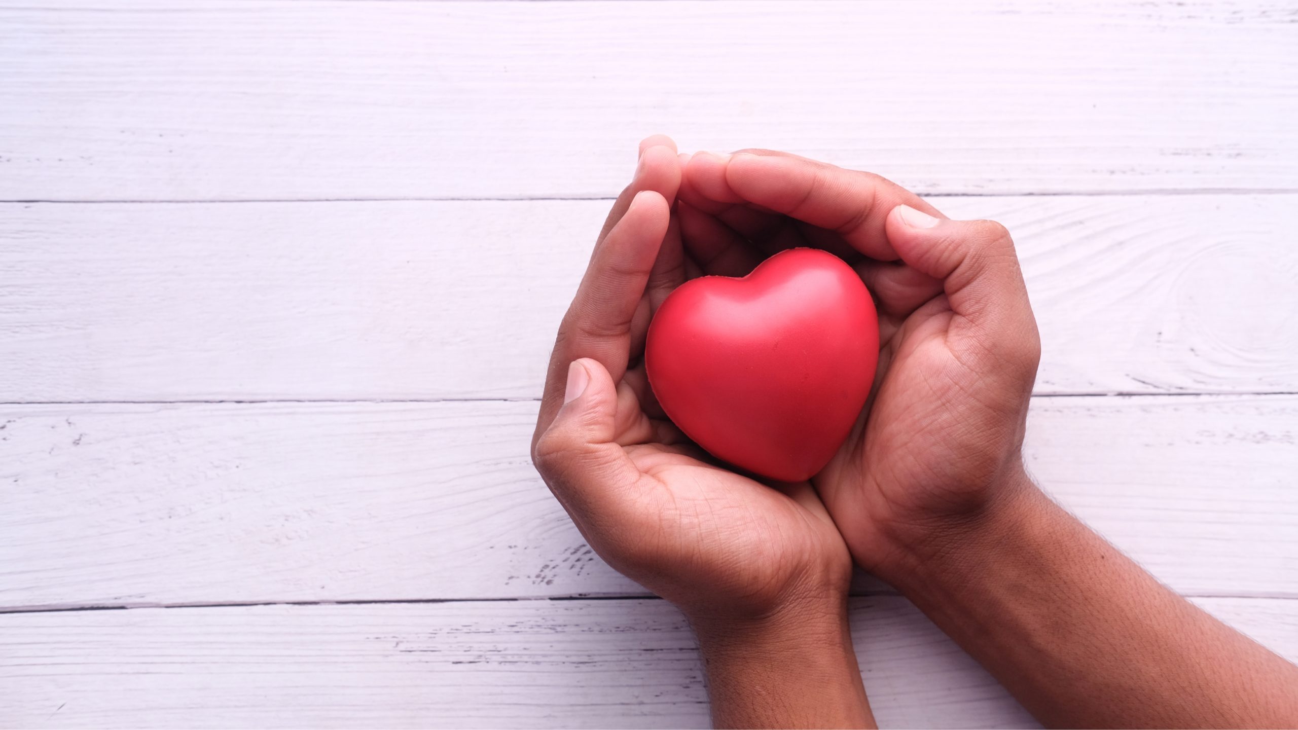 Manos sujetando un corazón rojo, simbolizando el apoyo y la esperanza en tratamientos de ovodonación y fertilidad.