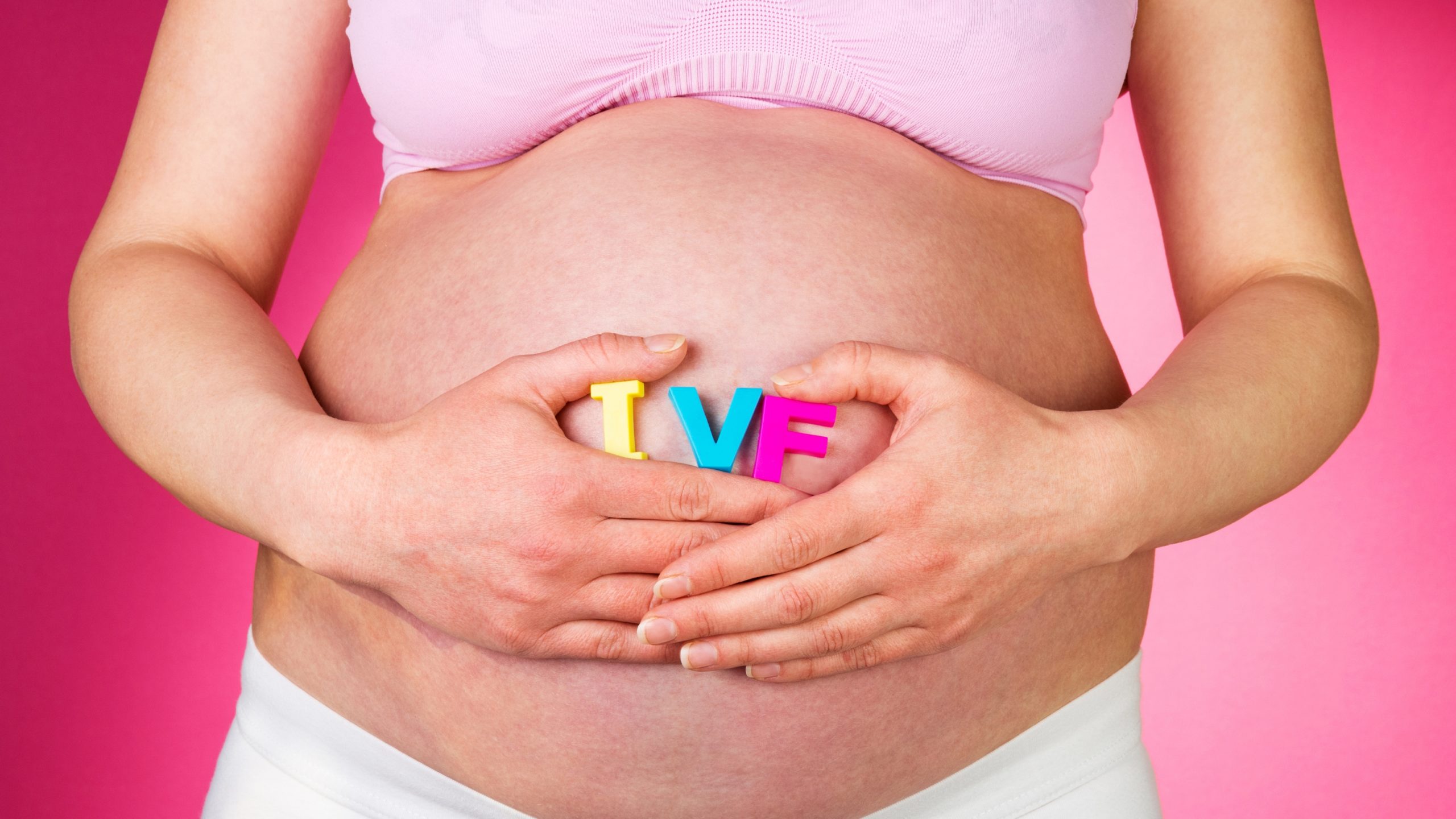 Vientre de mujer embarazada con letras “IVF”, representando un embarazo por fecundación in vitro con óvulos donados