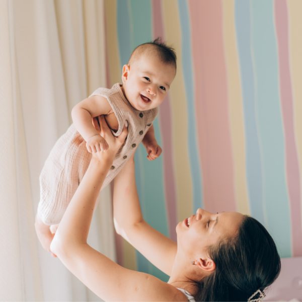 Madre levantando a su bebé con felicidad, representando el éxito de los tratamientos de fertilidad y reproducción asistida.