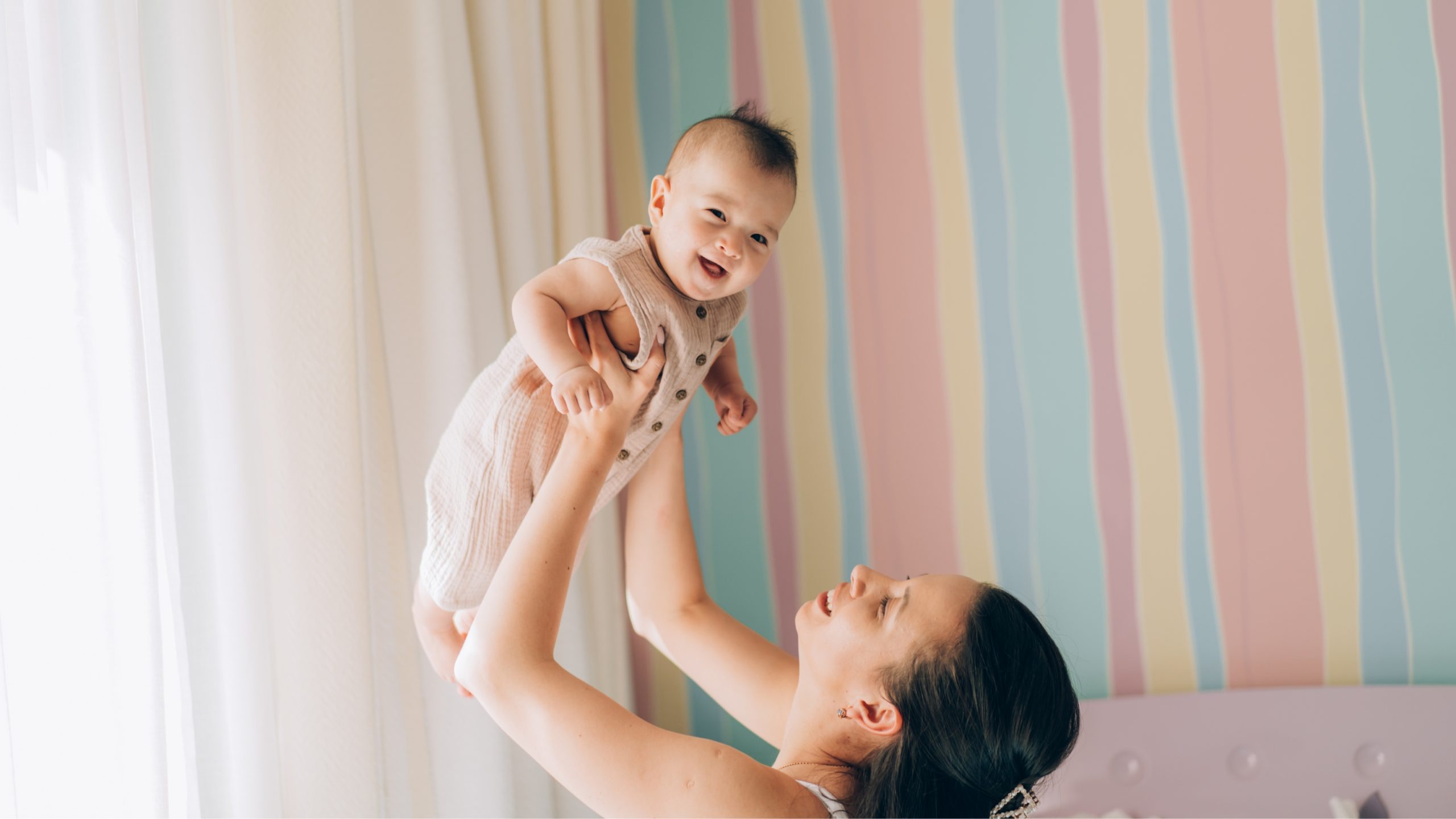 Madre levantando a su bebé con felicidad, representando el éxito de los tratamientos de fertilidad y reproducción asistida.